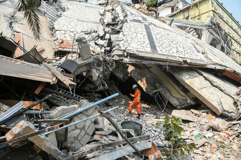 A rescue worker stands on rubble as teams attempt to free trapped residents at the destroyed Sky Villa Condominium development in Mandalay on March 29, 2025, a day after an earthquake struck central Myanmar. © AFP/Sai Aung MAIN