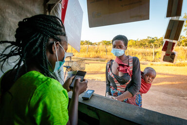 Naomi, a beneficiary from Zambia, visits a mobile money kiosk to withdraw her WFP cash assistance.