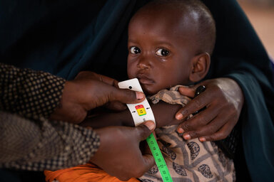 In this photo Mashallah (2) is held by his mother Dahera (28) while his MUAC is measured and he is assessed for malnutrition.