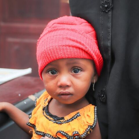 child in yellow shirt and pink hat