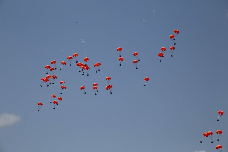 orange parachutes against clear blue sky