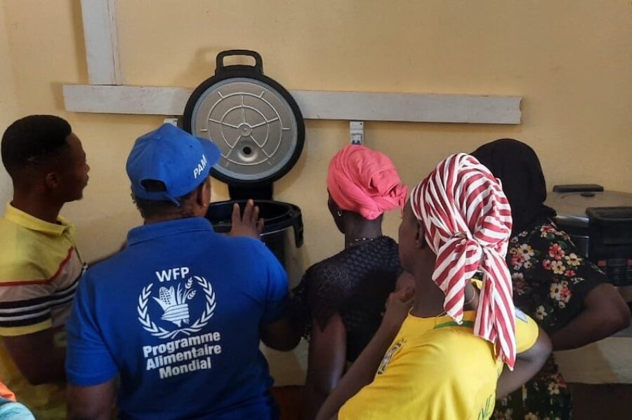 A WFP employee shows women in southern Guinea how to use solar-powered cookers to make WFP school meals. Photo: WFP/Youssouf Kaba