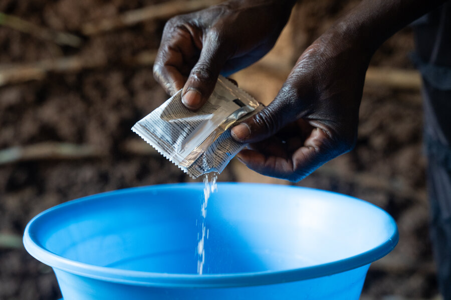 Wanjala prepares the Toothpick bioherbicide before coating her seeds with it, ahead of planting. Photo: WFP/Lisa Murray