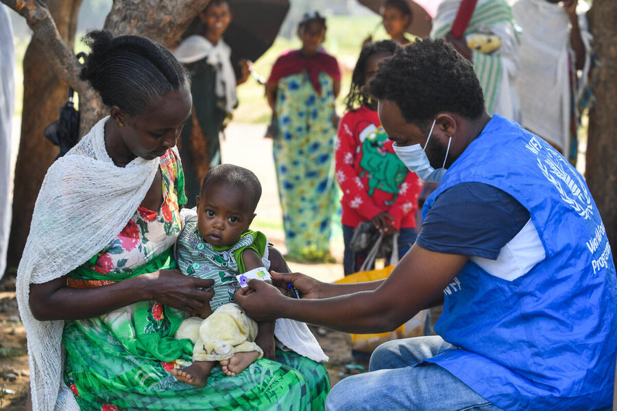 A WFP worker checks a child for malnutrition at a displacement camp in Ethiopia's Tigray region.  We may be forced to deeply cut assistance for millions of people in the country. Photo: WFP/Michael Tewelde