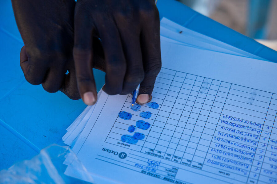 Close up of a paper form onto which a person registering for food assistance issues the latest fingerprint