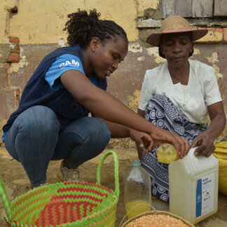 A WFP staff is helping a beneficiary to receive WFP food assistance.