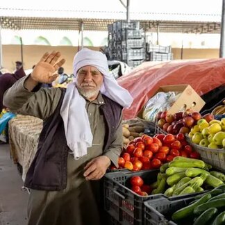 Man standing next to fruit stall in market