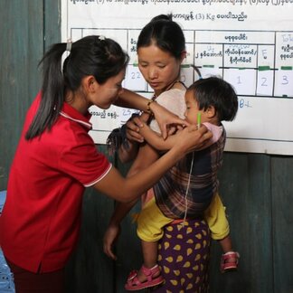 Health care assistant examining a child for malnutrition