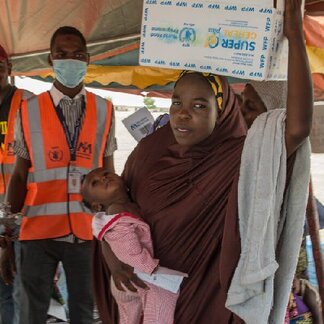 Zainab, and her daughter Kaltume Musa receiving a ration of Super Cereal plus after being measured to assess their need for supplementary nutritional support.