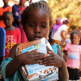 A child holding a bag of WFP nutritional supplement