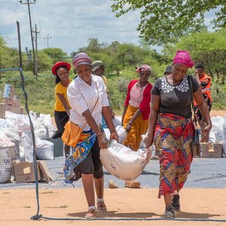 Two beneficiaries are carrying WFP sack