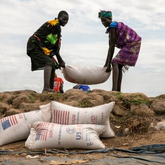 Two women carrying a sack of nutrient-rich food assistance distributed by WFP in South Sudan