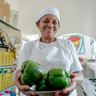 a chef is showing green peppers she is holding
