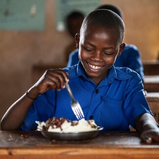 9-year-old Belyse and her classmates eat beans, ugali (maize flour) and spinach that is served for lunch at Bwama Primary school in Nyamagabe district, Rwanda on 27th of May 2021. Photo: WFP/Arete/Fredrik Lerneryd