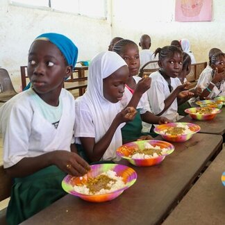 Schoolchildren eating nutritious meals provided by WFP. Photo: WFP/Mamadou Jallow