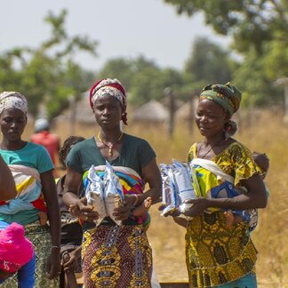 Two women with a child on their back, have just received packets of Corn Soya Blend (CSB+). Photo: WFP/Cheick Omar Bandaogo