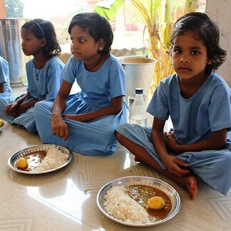 Three kids eating their school meal