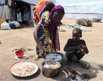 Woman and her children cooking with food assistance items distributed by WFP in North Eastern Nigeria